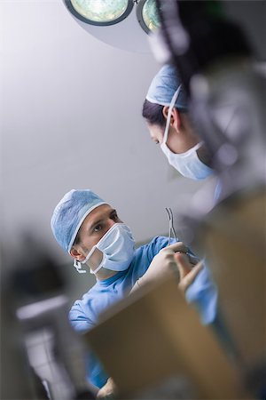 simsearch:400-06734297,k - Serious doctor giving a surgical scissor to a nurse in operating theater Stock Photo - Budget Royalty-Free & Subscription, Code: 400-06734516