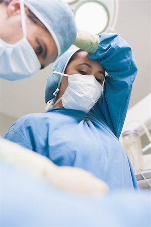 simsearch:400-06734297,k - Doctor putting her arm in her head in operating theater Stock Photo - Budget Royalty-Free & Subscription, Code: 400-06734527