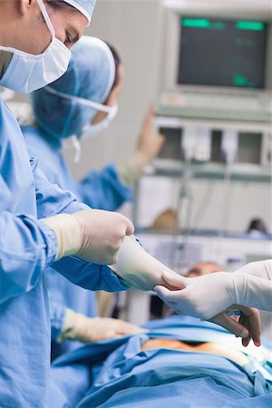 simsearch:400-06734297,k - Doctor removing his gloves in operating theater Stock Photo - Budget Royalty-Free & Subscription, Code: 400-06734528