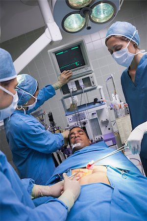 simsearch:400-06734297,k - Serious doctors operating a patient in operating theater Stock Photo - Budget Royalty-Free & Subscription, Code: 400-06734521