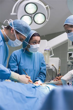 simsearch:400-06734297,k - Serious doctors operating a surgical tools in operating theater Stock Photo - Budget Royalty-Free & Subscription, Code: 400-06734523