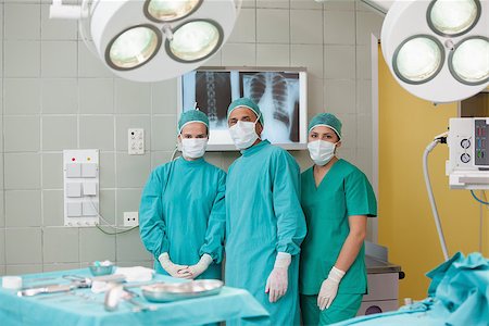 simsearch:400-06734297,k - Serious medical team looking at camera in operating theater Stock Photo - Budget Royalty-Free & Subscription, Code: 400-06734906