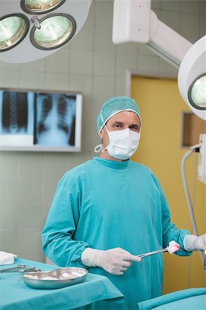 simsearch:400-06734297,k - Surgeon holding a surgical tool in operating theater Stock Photo - Budget Royalty-Free & Subscription, Code: 400-06734900