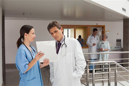 Two doctors standing in the hall of a hospital while looking at documents Stock Photo - Budget Royalty-Free & Subscription, Code: 400-06799509