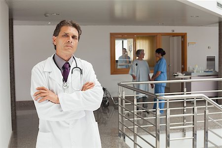 Doctor standing in the hallway while crossing his arms and looking serious Stock Photo - Budget Royalty-Free & Subscription, Code: 400-06799502