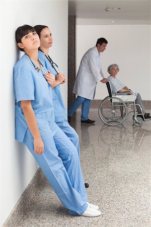 Two nurses leaning on wall with doctor pushing patient in wheelchair Stock Photo - Budget Royalty-Free & Subscription, Code: 400-06799524