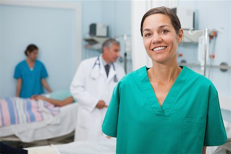 Nurse standing in hospital room with doctor and other nurse in background Stock Photo - Budget Royalty-Free & Subscription, Code: 400-06799604