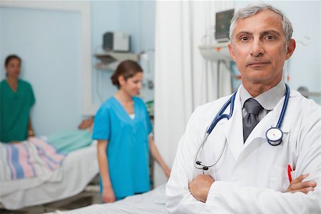 Doctor in hospital room with two nurses and a patient in the background Stock Photo - Budget Royalty-Free & Subscription, Code: 400-06799610