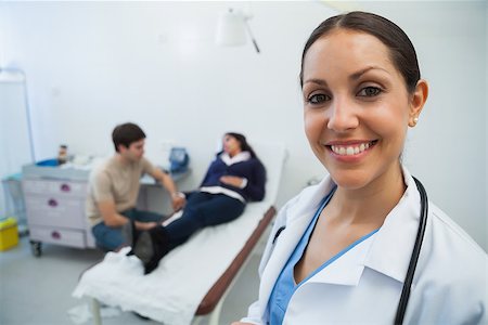 Doctor smiling in hospital room with patient in background Stock Photo - Budget Royalty-Free & Subscription, Code: 400-06799645