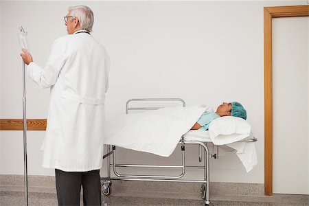 Doctor adjusting patient's IV drip in hospital corridor Stock Photo - Budget Royalty-Free & Subscription, Code: 400-06799685