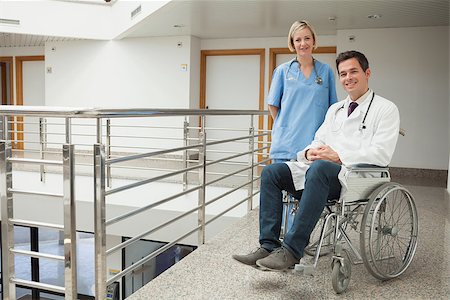 Nurse standing with doctor sitting in wheelchair in hospital corridor Stock Photo - Budget Royalty-Free & Subscription, Code: 400-06799814