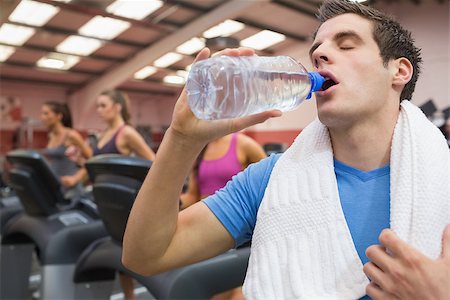 simsearch:400-05115517,k - Man drinking a bottle of water in the gym with towel around neck Stock Photo - Budget Royalty-Free & Subscription, Code: 400-06799855