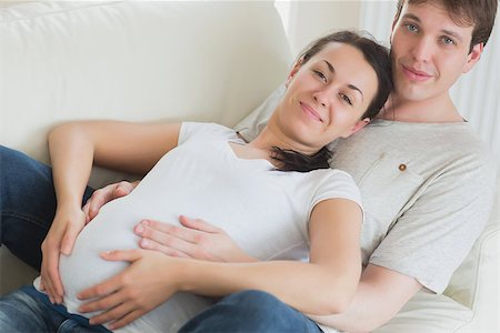 pregnant couple couch - Pregant woman and husband lying on couch toucher her belly Stock Photo - Budget Royalty-Free & Subscription, Code: 400-06800284