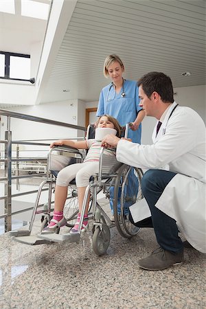 Doctor crouching next to child in wheelchair with neck brace with nurse pushing it Stock Photo - Budget Royalty-Free & Subscription, Code: 400-06800640