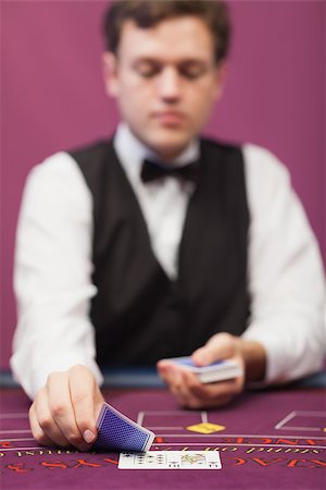 dealer (male) - Dealer sitting at table of a casino while holding and distributing cards Stock Photo - Budget Royalty-Free & Subscription, Code: 400-06802061