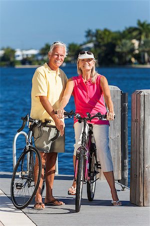 Happy senior man and woman couple together cycling on bicycles with bright clear blue sky by a river or sea Stock Photo - Budget Royalty-Free & Subscription, Code: 400-06856549
