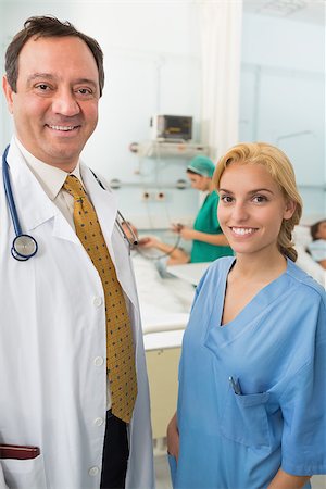 Smiling doctor and smiling nurse talking in a hospital ward where patients are resting Stock Photo - Budget Royalty-Free & Subscription, Code: 400-06868032