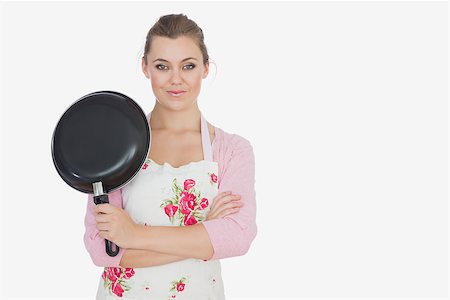 Portrait of young woman in apron holding frying pan over white background Stock Photo - Budget Royalty-Free & Subscription, Code: 400-06868739