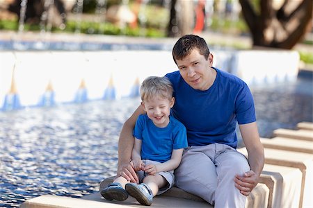 family of two enjoying time together outdoors, young handsome father and his adorable son laughing with his eyes shut sitting by the fountain Stock Photo - Budget Royalty-Free & Subscription, Code: 400-06862183