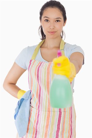 simsearch:400-06863660,k - Smiling woman spraying cleaner in apron and rubber gloves Stock Photo - Budget Royalty-Free & Subscription, Code: 400-06863614