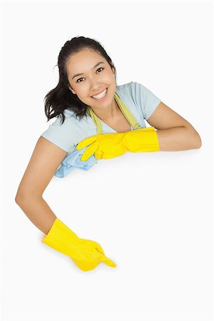 simsearch:400-06863660,k - Happy cleaning lady in rubber gloves and apron pointing to white surface Stock Photo - Budget Royalty-Free & Subscription, Code: 400-06863659
