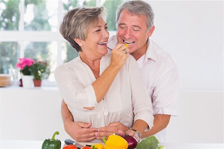Old man tasting vegetable held by wife in kitchen Stock Photo - Budget Royalty-Free & Subscription, Code: 400-06874651