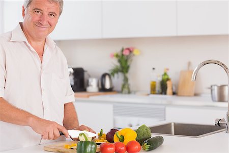 Old man smiling and preparing vegetables in kitchen Photographie de stock - Aubaine LD & Abonnement, Code: 400-06874664