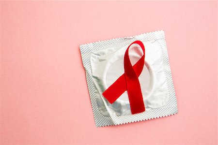 Red awareness ribbon lying on condom in wrapper on pink background Stock Photo - Budget Royalty-Free & Subscription, Code: 400-06876144