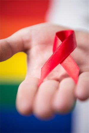 equality background hands - Man holding red aids awareness ribbon close up on rainbow background Stock Photo - Budget Royalty-Free & Subscription, Code: 400-06876234