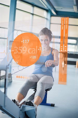 Front view of an attractive girl on rowing machine with futuristic interface showing calories Stock Photo - Budget Royalty-Free & Subscription, Code: 400-06877646