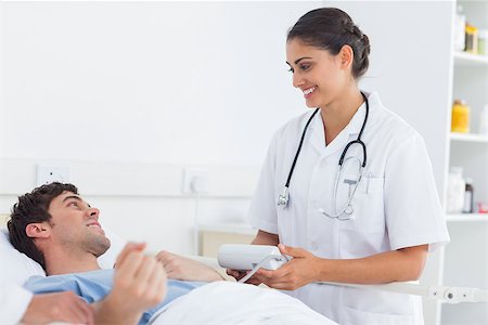 simsearch:400-05748252,k - Attractive doctor taking the blood pressure of a patient in a hospital Stock Photo - Budget Royalty-Free & Subscription, Code: 400-06879534