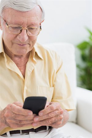 phone one person adult smile elderly - Focused elderly man using his smartphone on a sofa Stock Photo - Budget Royalty-Free & Subscription, Code: 400-06873143