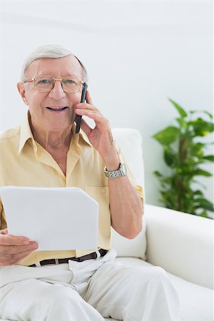 phone one person adult smile elderly - Elderly smiling man reading papers on the phone on a sofa Stock Photo - Budget Royalty-Free & Subscription, Code: 400-06873151