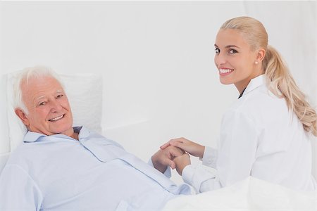 Smiling doctor holding hand of elderly patient in bed Stock Photo - Budget Royalty-Free & Subscription, Code: 400-06873623