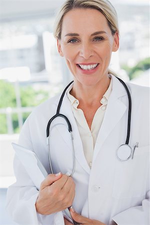 Attractive doctor standing with a clipboard in a modern workplace Stock Photo - Budget Royalty-Free & Subscription, Code: 400-06884177