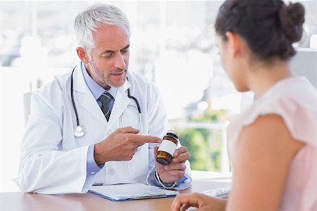doctor consulting patient tablet - Doctor explaining the bottle of pills to patient in the office at desk Stock Photo - Budget Royalty-Free & Subscription, Code: 400-06884949
