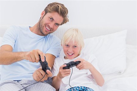 simsearch:400-06872329,k - Cheerful father and son playing video games in bed Stock Photo - Budget Royalty-Free & Subscription, Code: 400-06886547