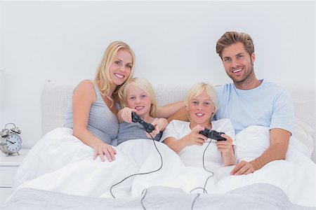 simsearch:400-06872329,k - Family playing video games in bed Stock Photo - Budget Royalty-Free & Subscription, Code: 400-06886586