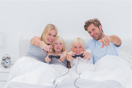 simsearch:400-06872329,k - Happy family playing video games in bed Stock Photo - Budget Royalty-Free & Subscription, Code: 400-06886587