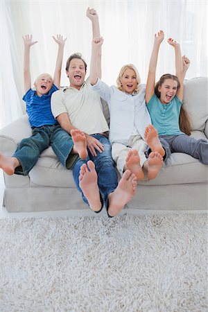 Portrait of a family watching television and raising arms sitting on a couch Stock Photo - Budget Royalty-Free & Subscription, Code: 400-06887755