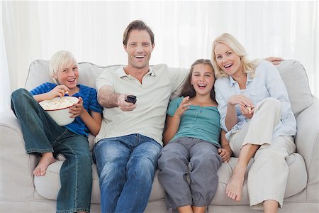 Family watching television sitting on sofa with pop corn Stock Photo - Budget Royalty-Free & Subscription, Code: 400-06887750