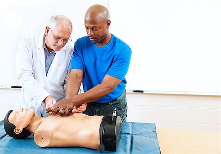 simsearch:400-07411030,k - Doctor teaching first aid CPR techniques to an adult, African-american student.  Room for text. Stock Photo - Budget Royalty-Free & Subscription, Code: 400-06917332
