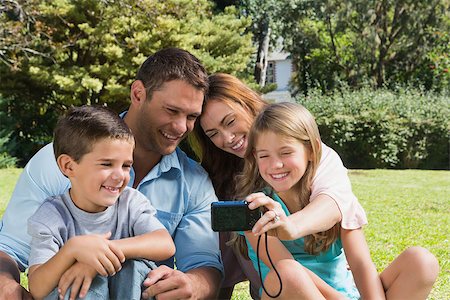 family and park and camera - Laughing family looking at pictures in their camera in the park Stock Photo - Budget Royalty-Free & Subscription, Code: 400-06934059