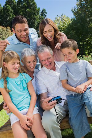 Multi generation family looking at photos on a park bench Stock Photo - Budget Royalty-Free & Subscription, Code: 400-06934107