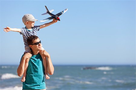 happy adorable boy holding toy plane and sitting on his young handsome father shoulders and having fun together outdoors Photographie de stock - Aubaine LD & Abonnement, Code: 400-06947516