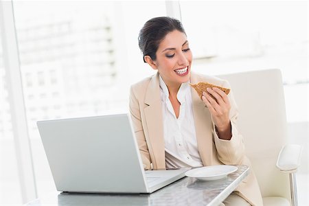 Happy businesswoman eating lunch as she is working at the office Stock Photo - Budget Royalty-Free & Subscription, Code: 400-06958792