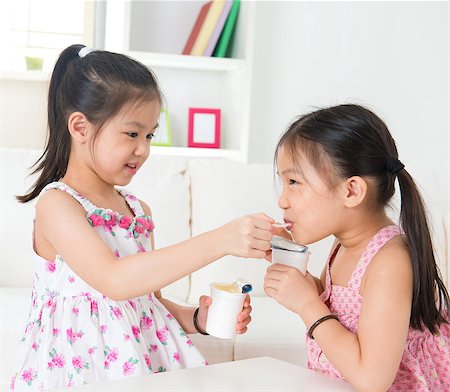 simsearch:400-07171482,k - Eating yogurt. Happy Asian children eating yoghurt at home. Beautiful sisters . Healthcare concept. Stock Photo - Budget Royalty-Free & Subscription, Code: 400-07046763