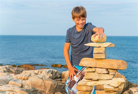 Boy building inukshuk on the rocky beach (Duncan Cove, Nova Scotia, Canada) Stock Photo - Budget Royalty-Free & Subscription, Code: 400-07048305