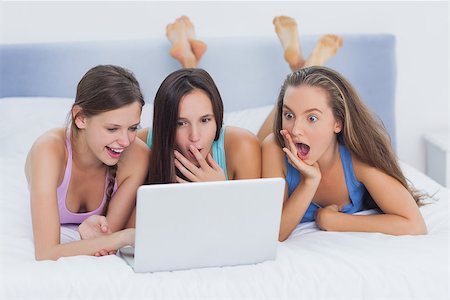 Girls on bed looking shocked at laptop Stock Photo - Budget Royalty-Free & Subscription, Code: 400-07057389
