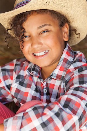 A beautiful and happy mixed race African American female girl child wearing straw cowboy hat and plaid shirt sitting in hay filled barn Stock Photo - Budget Royalty-Free & Subscription, Code: 400-07053729